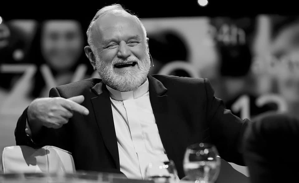 Czarno białe zdjęcie śmiejącego się Księdza Kanonika Paweła Pawlickiego.